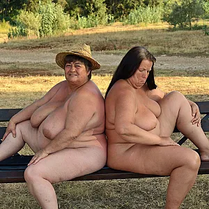 Two buxom lesbians posing naked on a bench 1 gallery image